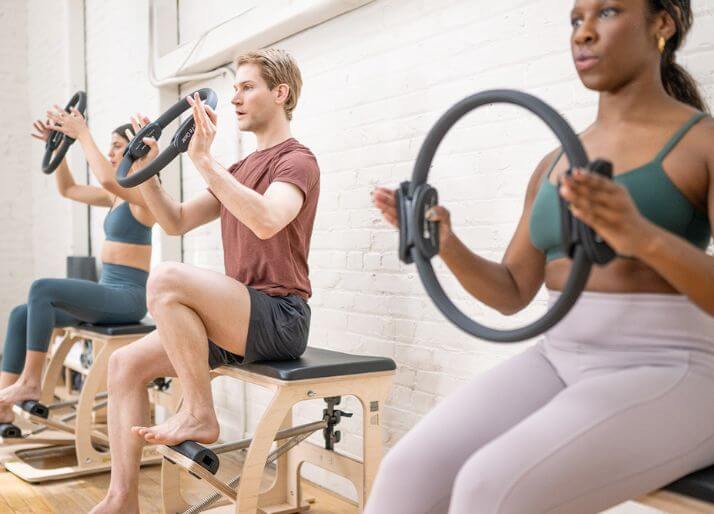 ピラティスのマシン「チェア」に乗って、ピラティスサークルでエクササイズする生徒たち