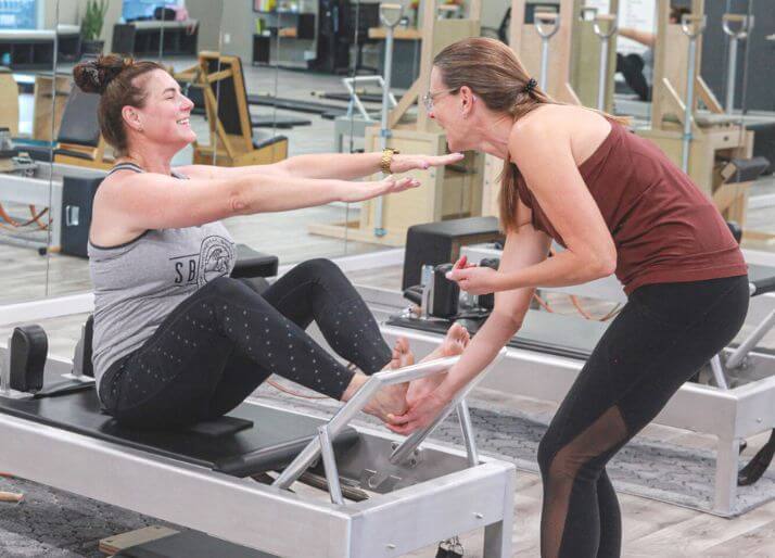 ピラティスのマシン「リフォーマー」に乗って、ティーチングの勉強をする生徒と先生