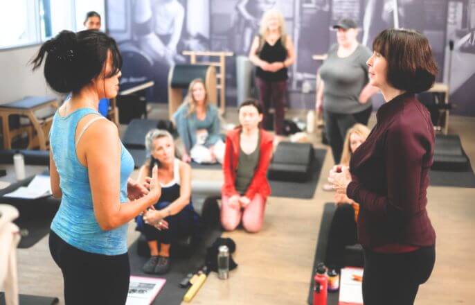 ピラティススタジオで教え合うインストラクターと生徒